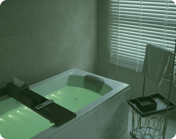 Green-lit oxygen bathtub therapy room at Oxygena Wellness